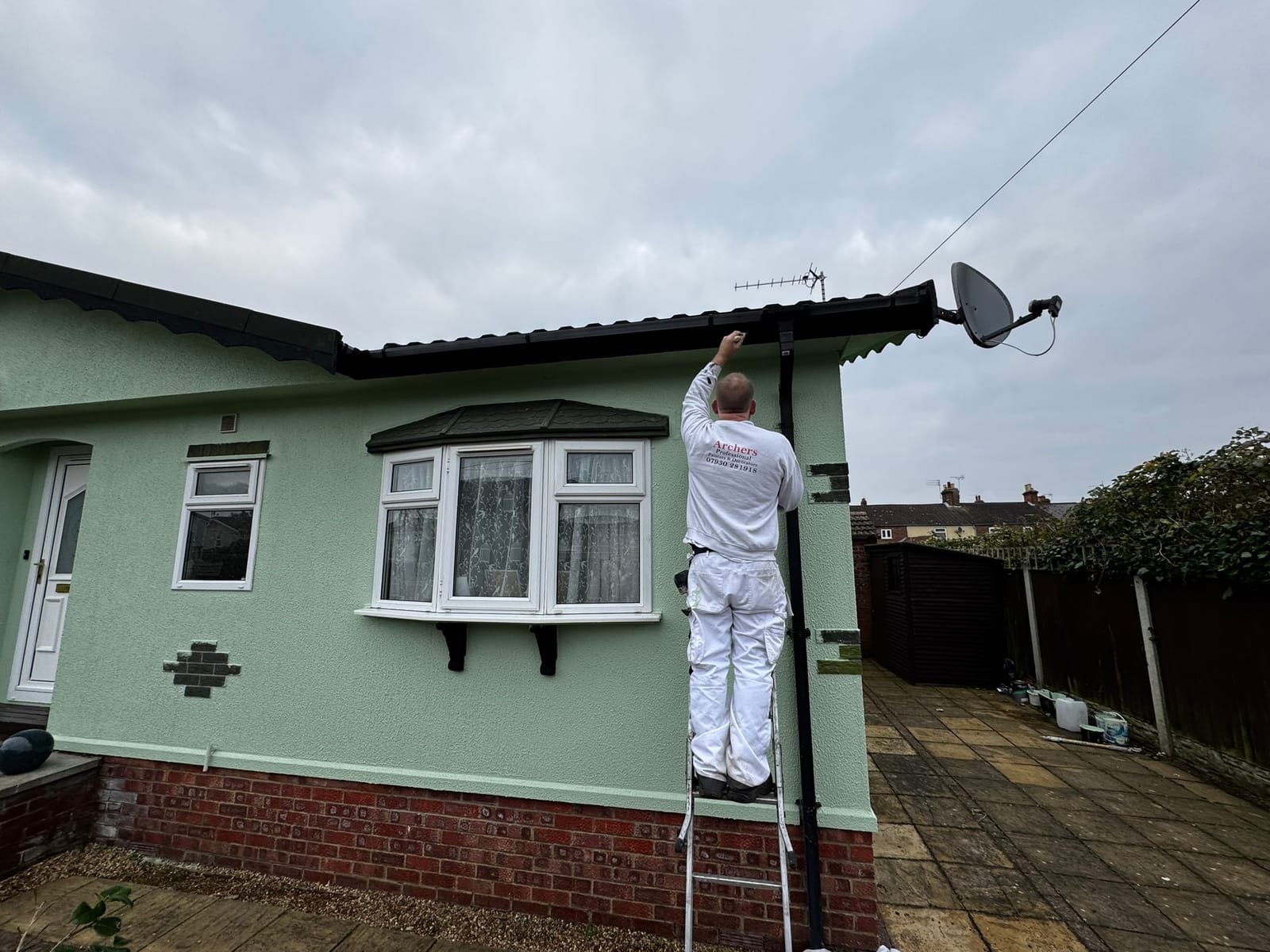 An Archers decorator repainting the exterior of a home near Lowestoft